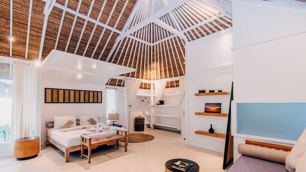 Una habitación amplia con una cama grande, un banco de madera, una mesa redonda y un televisor.