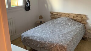 Ein Schlafzimmer mit Bett, einer Pendelleuchte, einem Fenster und einer Heizung.