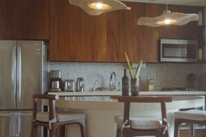 A modern kitchen with wooden cabinets, stainless steel appliances, and pendant lighting. - Walk to Beach - Luxury 2 bed 2 bath at Armadillo (Zihuatanejo)