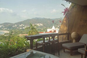 A terrace with a table and chairs, overlooking a coastal landscape with hills and buildings. - Walk to Beach - Luxury 2 bed 2 bath at Armadillo (Zihuatanejo)