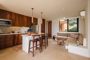 Une cuisine moderne dotée d’un îlot central, de meubles en bois et d’un four à micro-ondes encastré.
