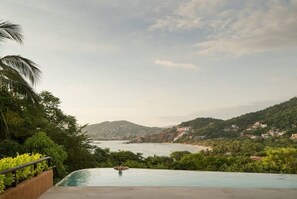 Une piscine avec vue sur une plage et des collines.