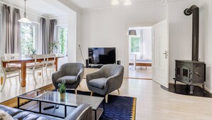 Uma sala de estar espaçosa com lareira moderna, assentos confortáveis e uma televisão.