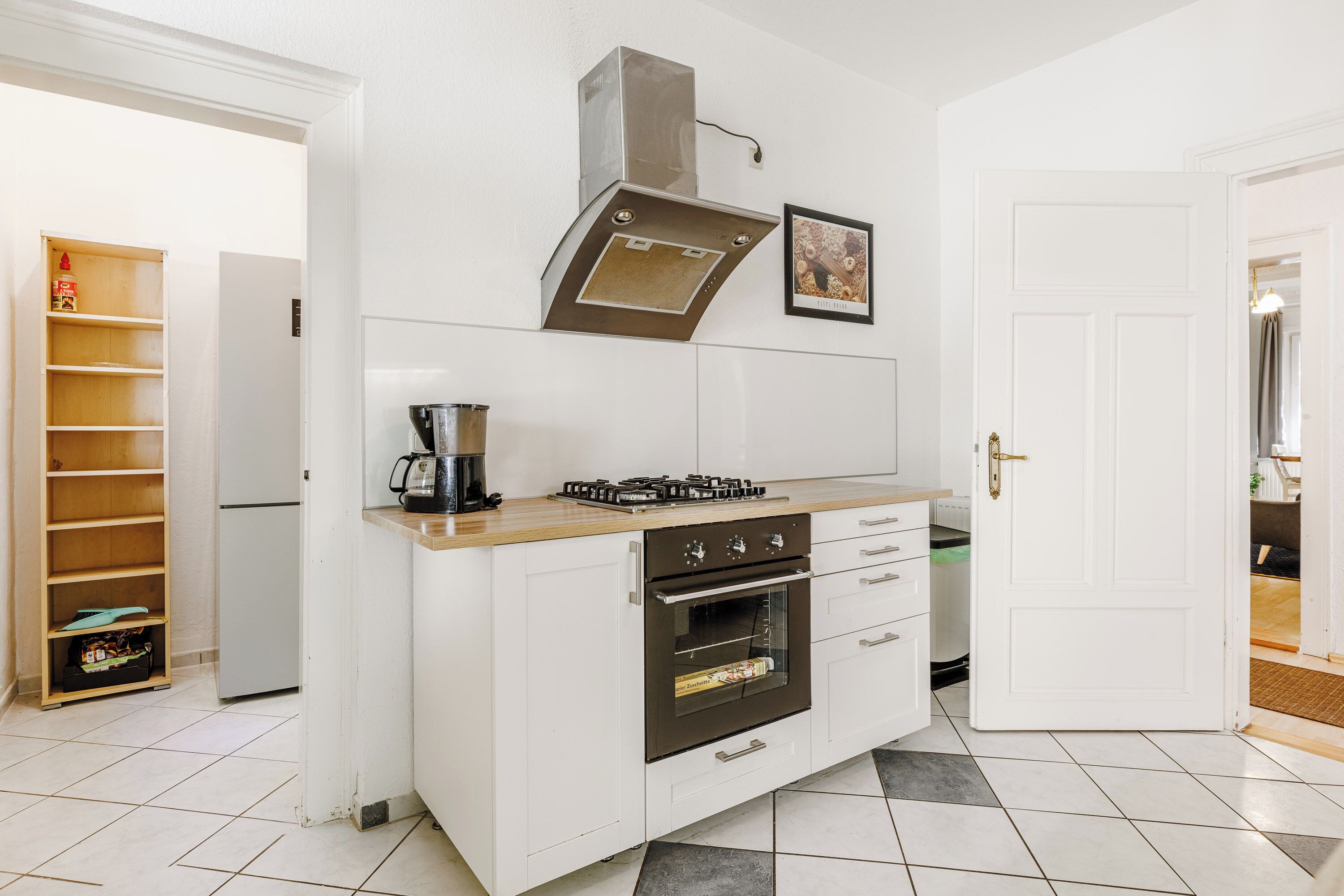 A compact kitchen with a built-in oven, a gas stove, and a stainless steel range hood.