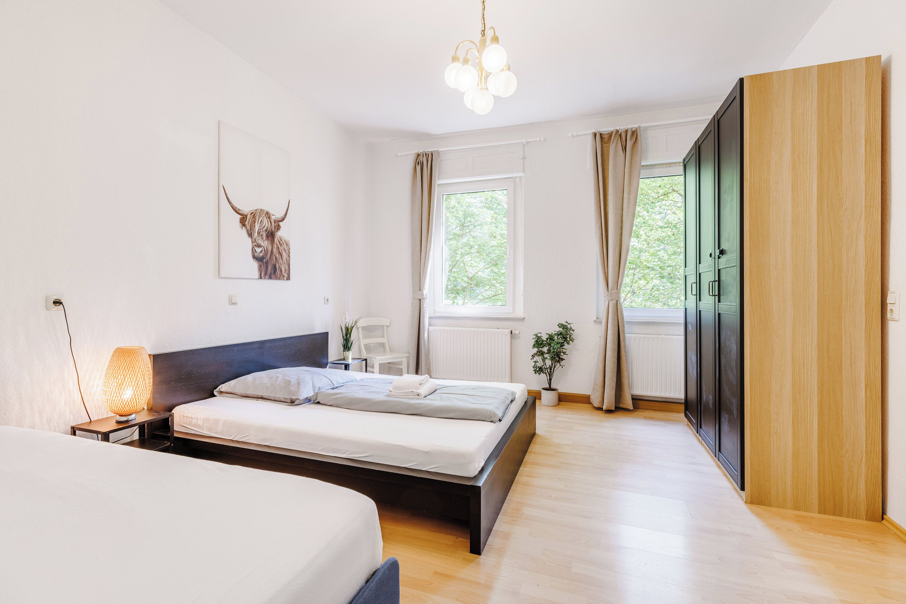 Ein modernes Schlafzimmer mit einem großen Bett, Nachttischen, einer Lampe, einem Fenster mit Vorhängen und einer Tür.