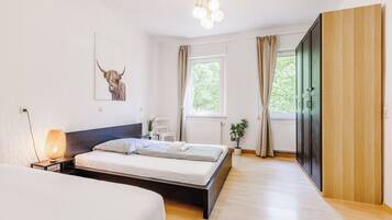Ein modernes Schlafzimmer mit einem großen Bett, Nachttischen, einer Lampe, einem Fenster mit Vorhängen und einer Tür.