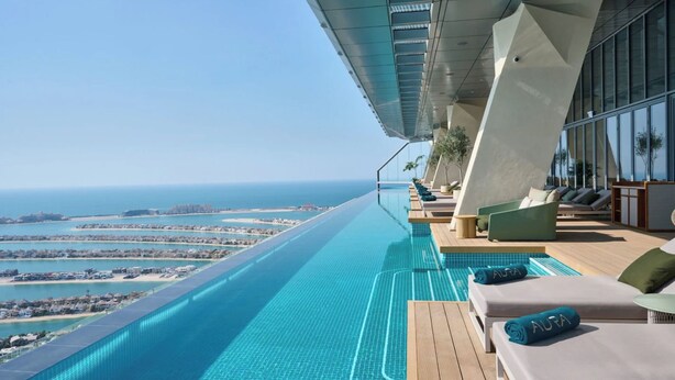 A modern infinity pool with a clear view of the coastline and cityscape. - WYZ RENT|Palm Tower 1 BD Nakheel Mall High Floor (Dubai)