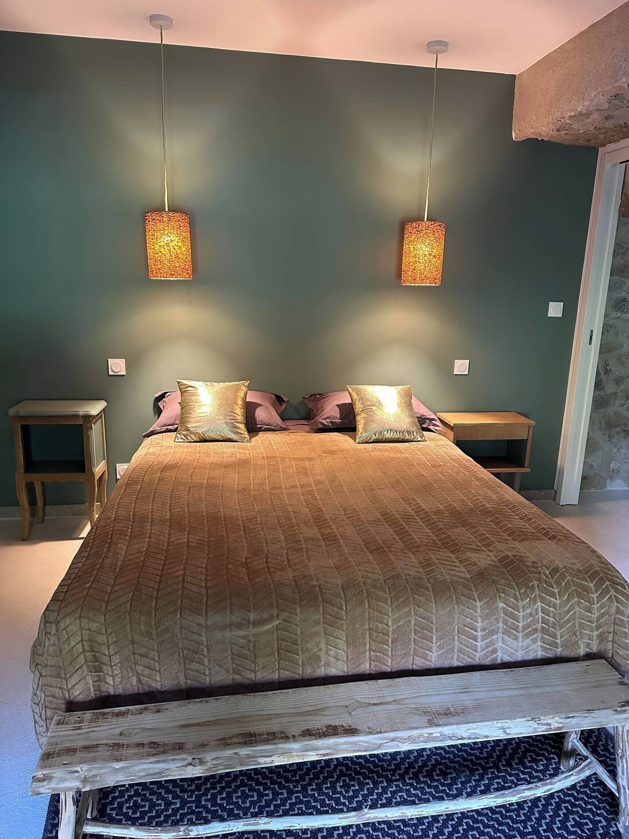 A bed with a patterned bedspread, two bedside tables, and two wall-mounted lamps.