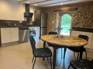 Enjoy cooking in this well-equipped kitchen with a central island, stainless steel appliances, and a dining area with black chairs.