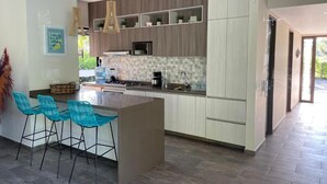 A modern kitchen with a central island, bar stools, and built-in shelving.