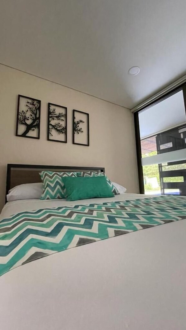 Un dormitorio con una cama, una ventana y tres cuadros colgados en la pared.