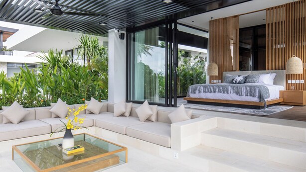 Un dormitorio moderno con una cama grande, un sofá y una mesa de centro de cristal.