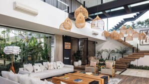Una sala de estar moderna con un sofá blanco, una mesa de centro de madera y lámparas colgantes de mimbre.