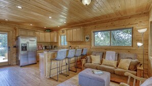Interior de una cabaña de madera con cocina, comedor y sala de estar.