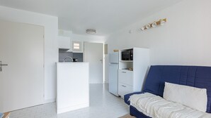 Un espacio habitable compacto con kitchenette, un sofá y un microondas.