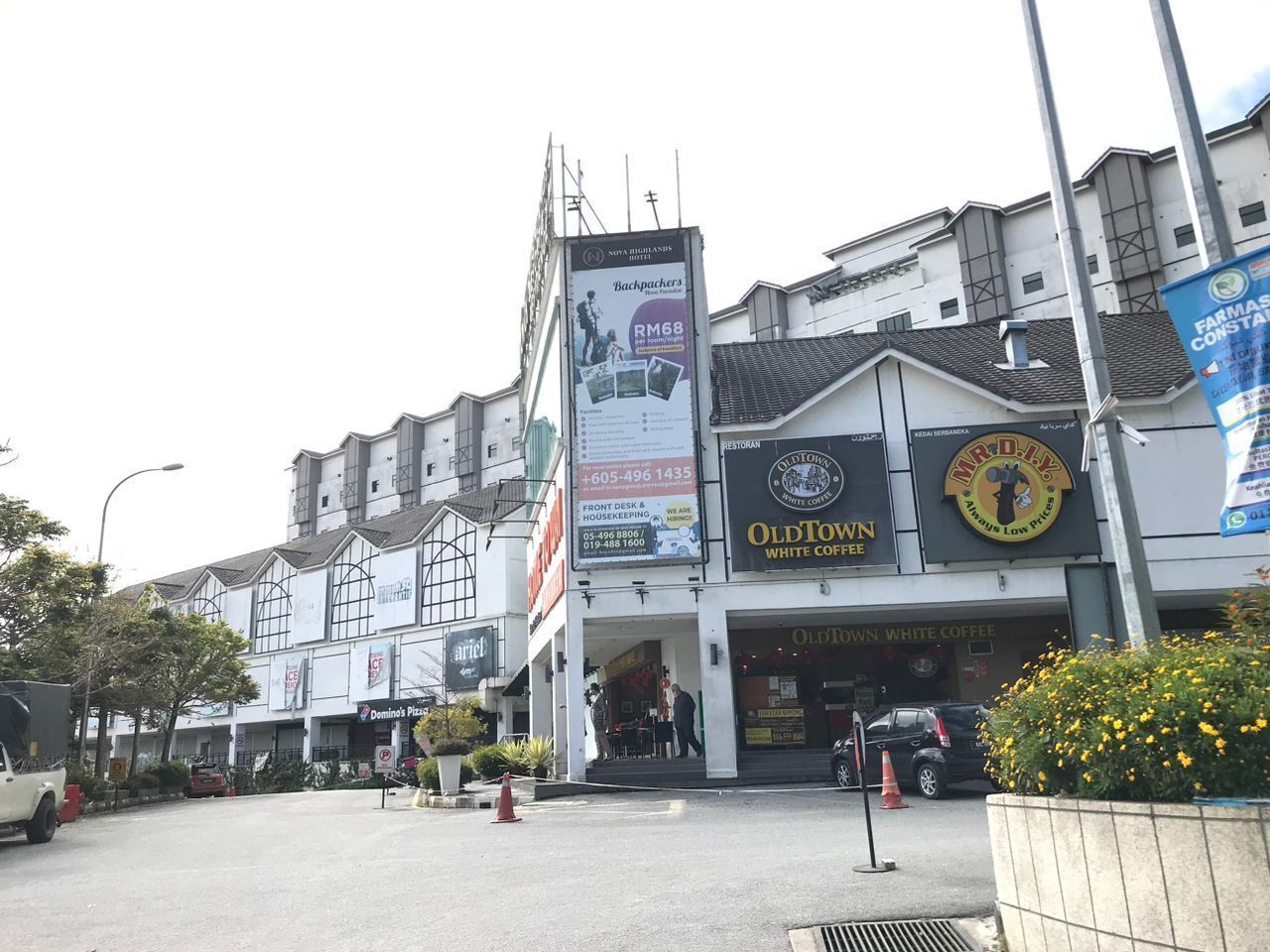 A building with multiple businesses including a Domino's Pizza, a restaurant named Old Town White Coffee, and a sign for a hotel named Noya Highland's Hotel.