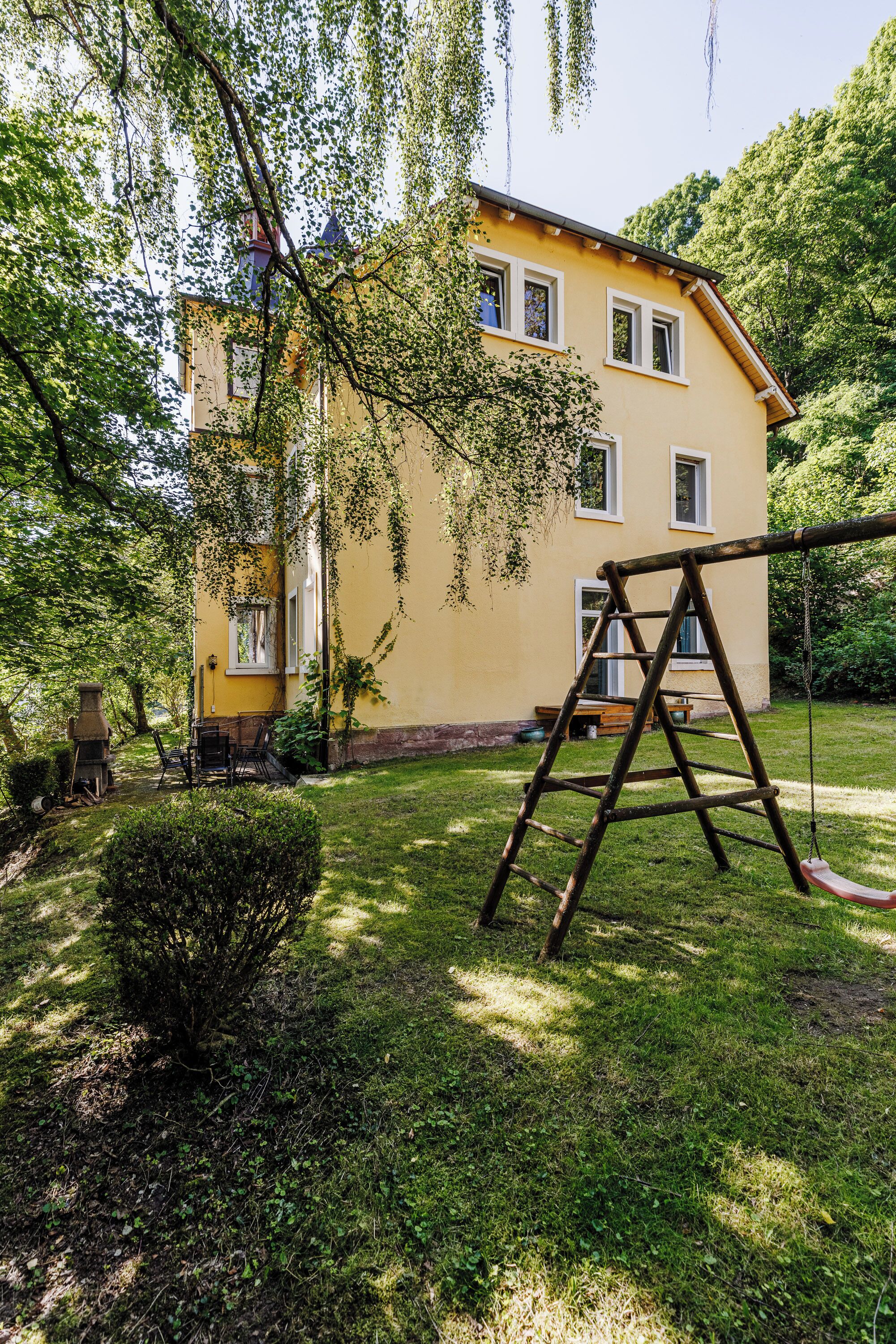 A yellow house with a swing set in the yard.