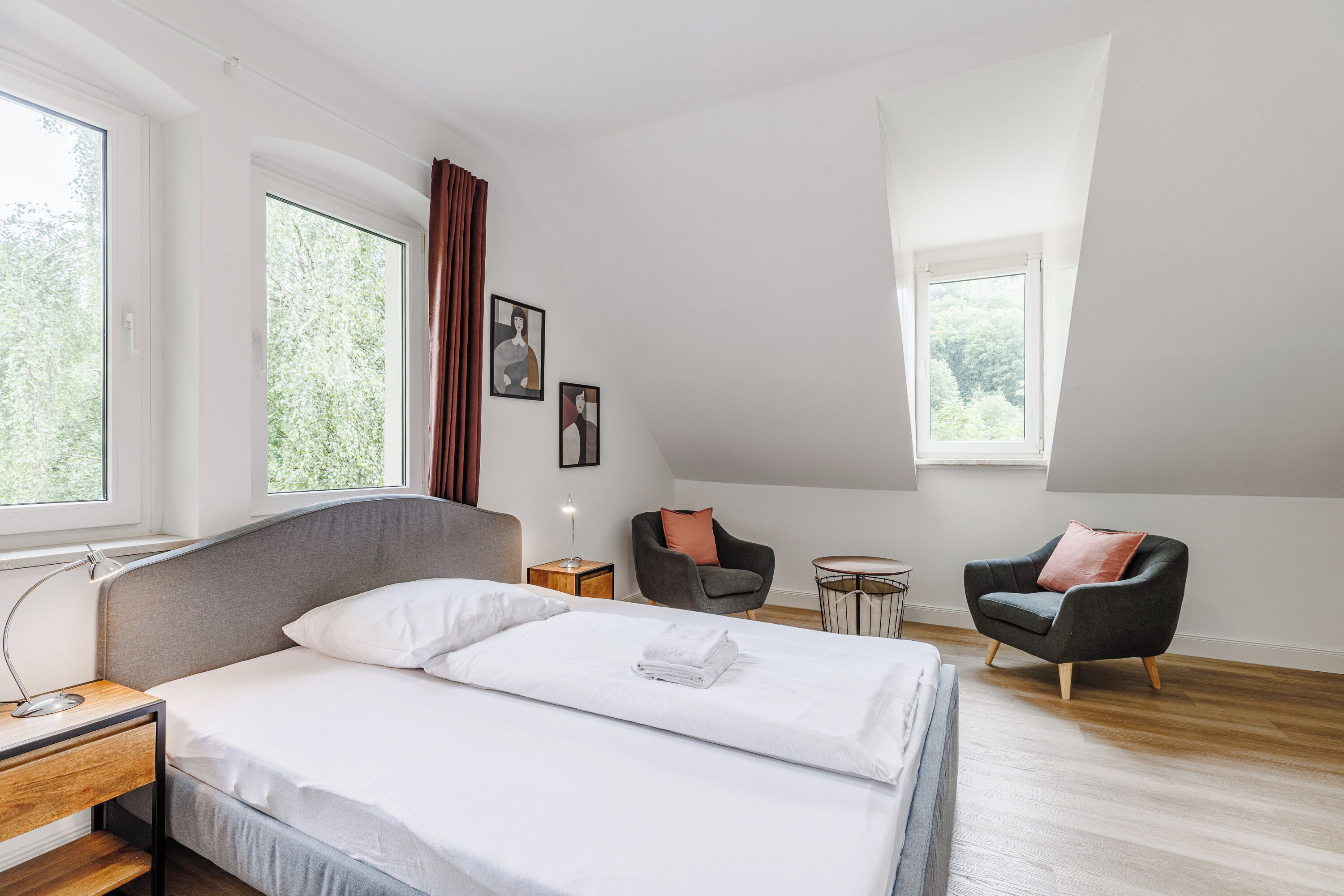 Moderni hotellihuone, jossa on suuri sänky, työpöytä, tuoli ja pieni pöytä.