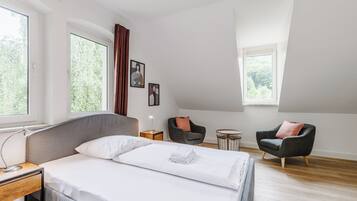 Moderni hotellihuone, jossa on suuri sänky, työpöytä, tuoli ja pieni pöytä.