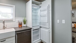 Una cocina con refrigerador integrado, un lavamanos y una ventana con persianas.