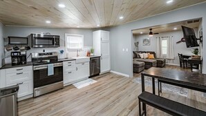 Una cocina moderna con armarios blancos, electrodomésticos de acero inoxidable y suelo de madera.