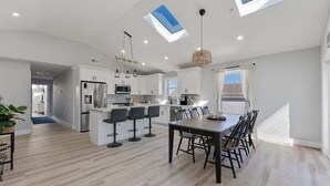 Een moderne keuken met een centraal eiland, barstoelen en een eettafel met stoelen.