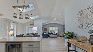 Een ruime woonkamer met een groot kookeiland, een eethoek en een zithoek met een bank en stoelen.