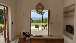 Una sala de estar moderna con un sofá, un banco de madera y un televisor sobre una estantería.