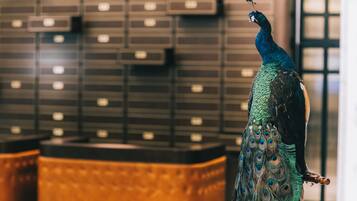 A peacock statue in a lobby with a patterned wall and a wooden bench.