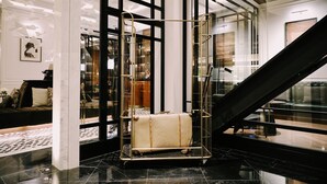 A modern lobby with a large window, a staircase, and a display case with a vintage suitcase. - Yangon Excelsior Hotel (Yangon)