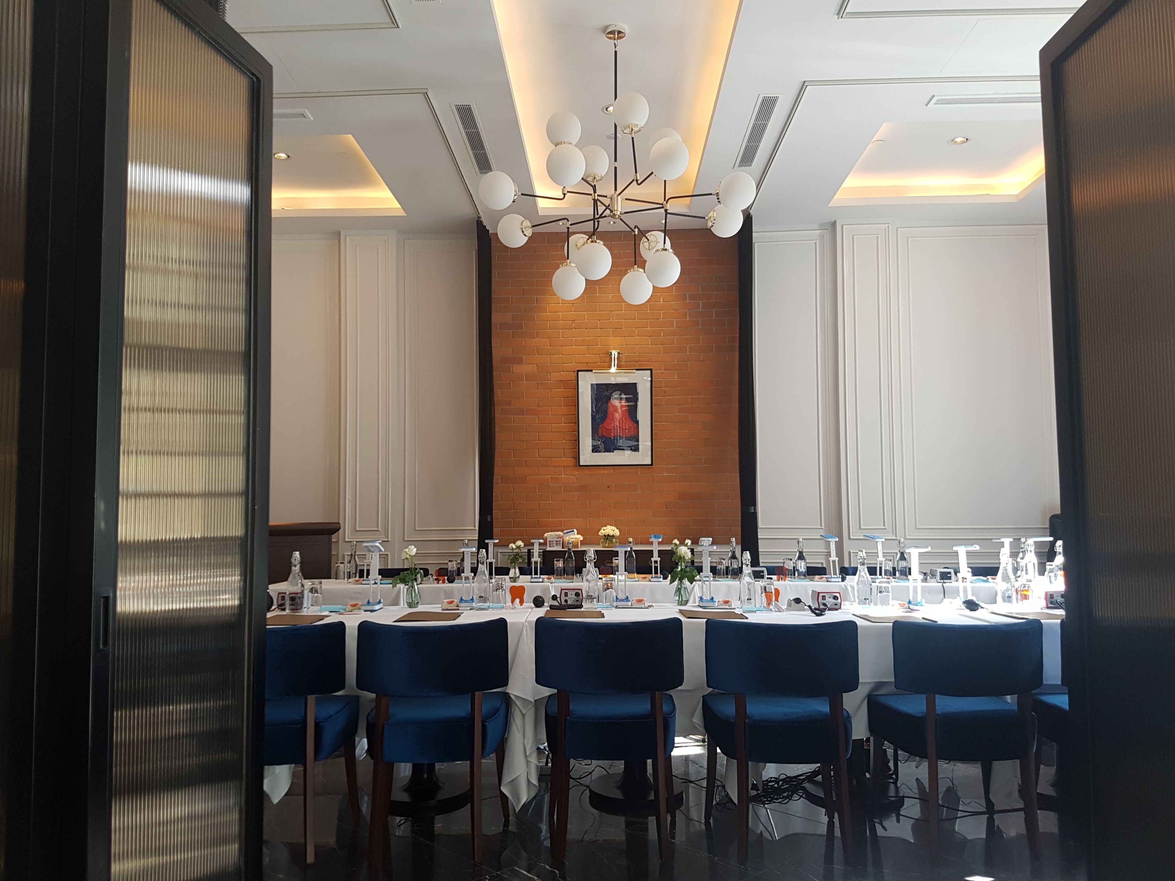 A conference room with a long table, blue chairs, and a chandelier.