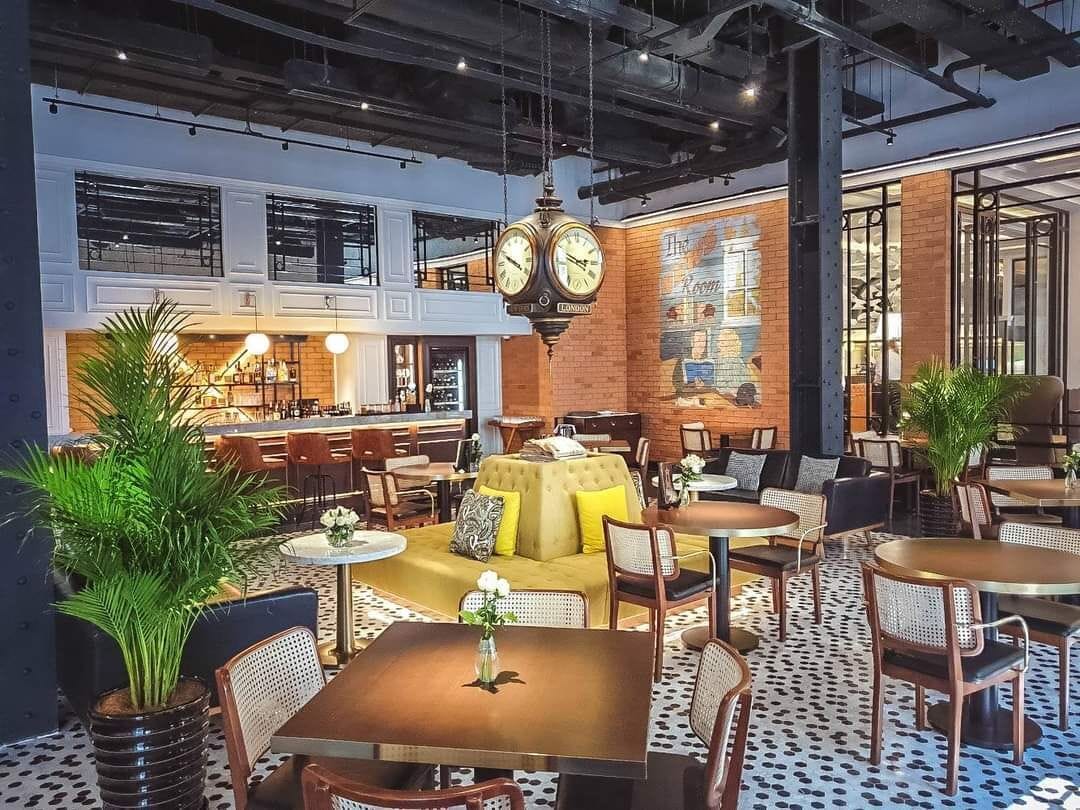 A modern lounge area with multiple seating options, including sofas and tables, and a large clock on the wall.