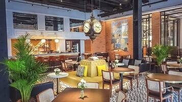 A modern lounge area with multiple seating options, including sofas and tables, and a large clock on the wall.
