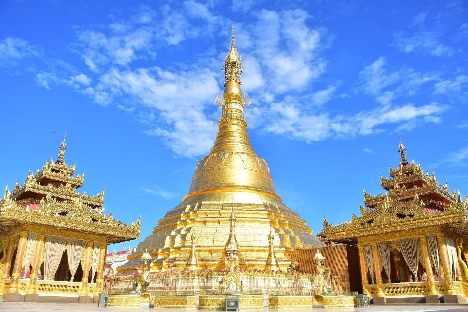 A large golden stupa with intricate designs, flanked by smaller structures with ornate details.