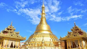 A large golden stupa with intricate designs, flanked by smaller structures with ornate details.