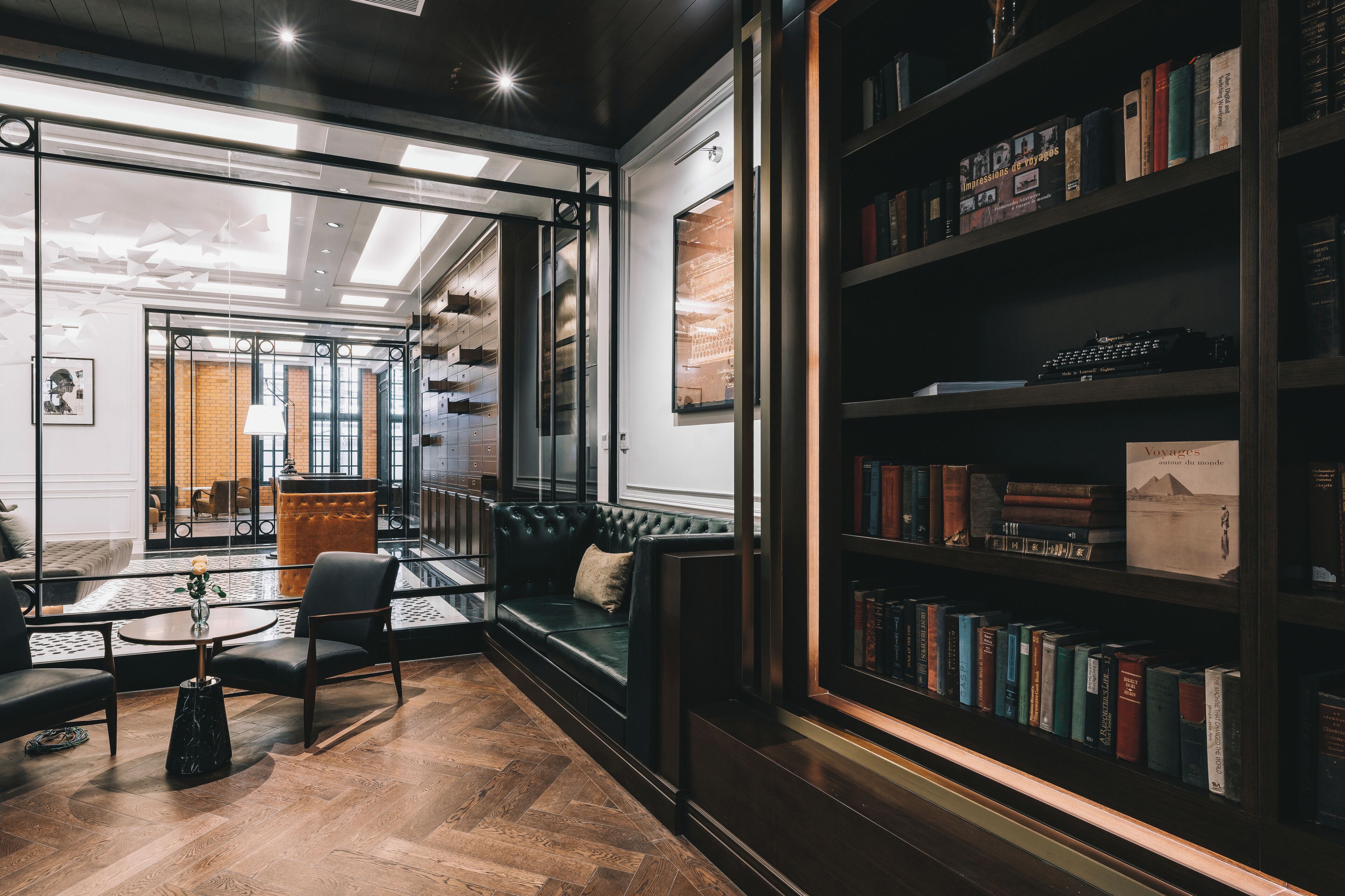 Een moderne bibliotheek met een leren bank, een glazen tafel en een boekenkast vol boeken.