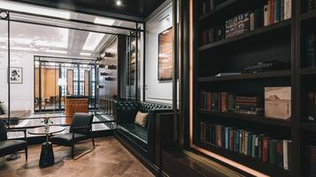 Een moderne bibliotheek met een leren bank, een glazen tafel en een boekenkast vol boeken.