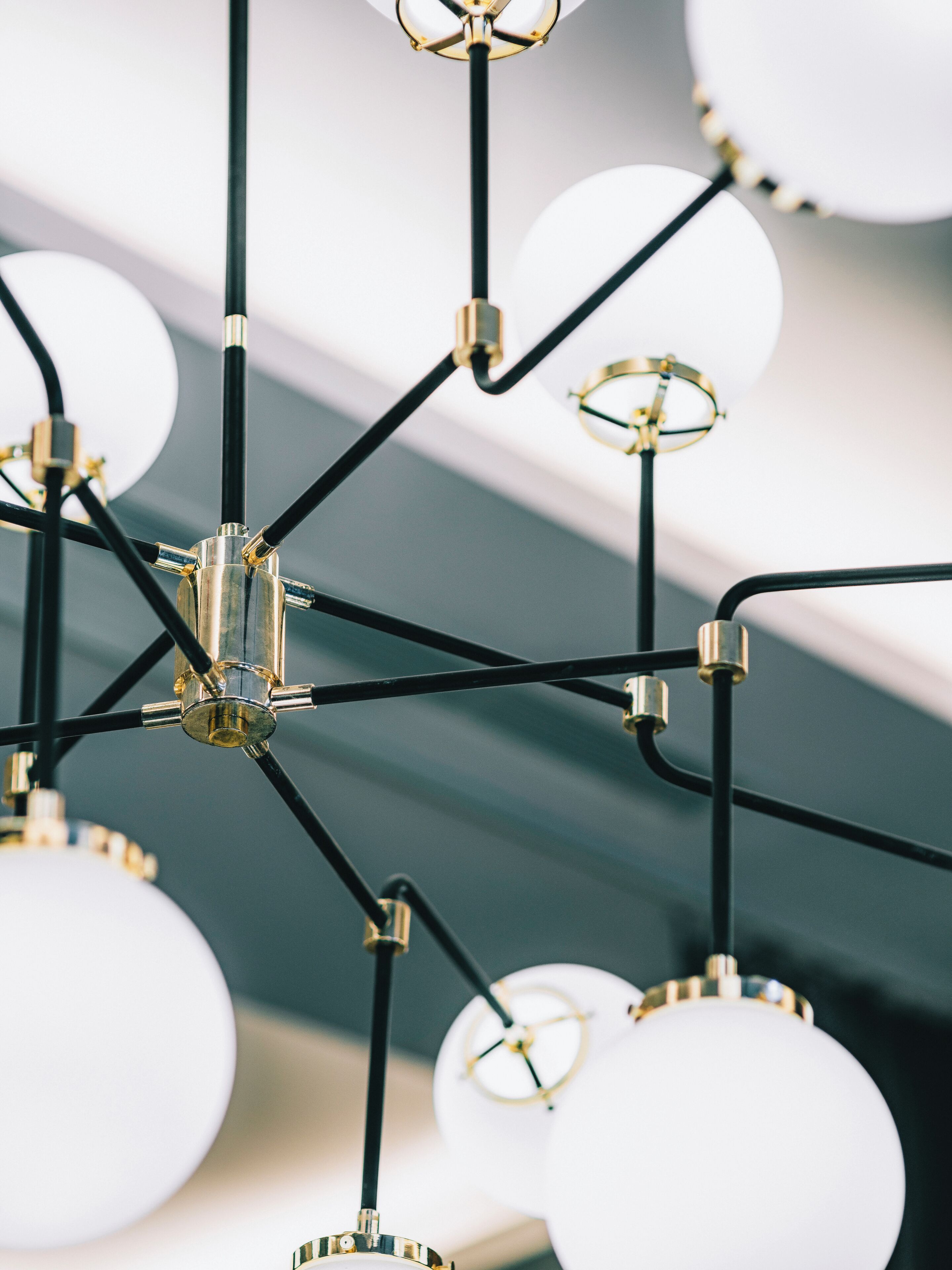 Een kroonluchter met meerdere bolvormige lampen en zwarte metalen armen.