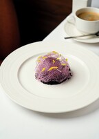 Un postre sobre un plato blanco, con una taza de café al fondo.