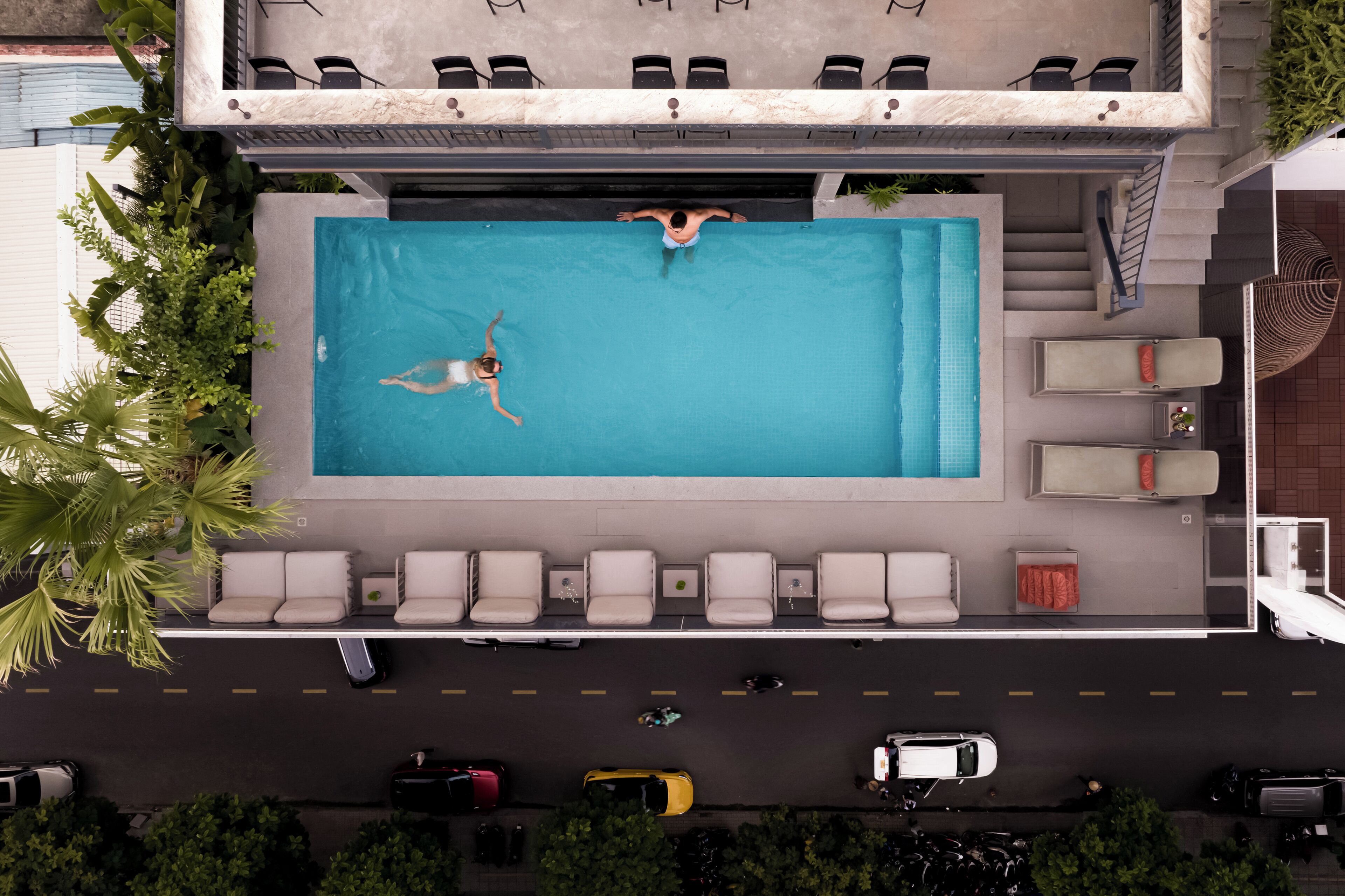Vue aérienne d’un hôtel avec une piscine, des chaises longues et un parking.
