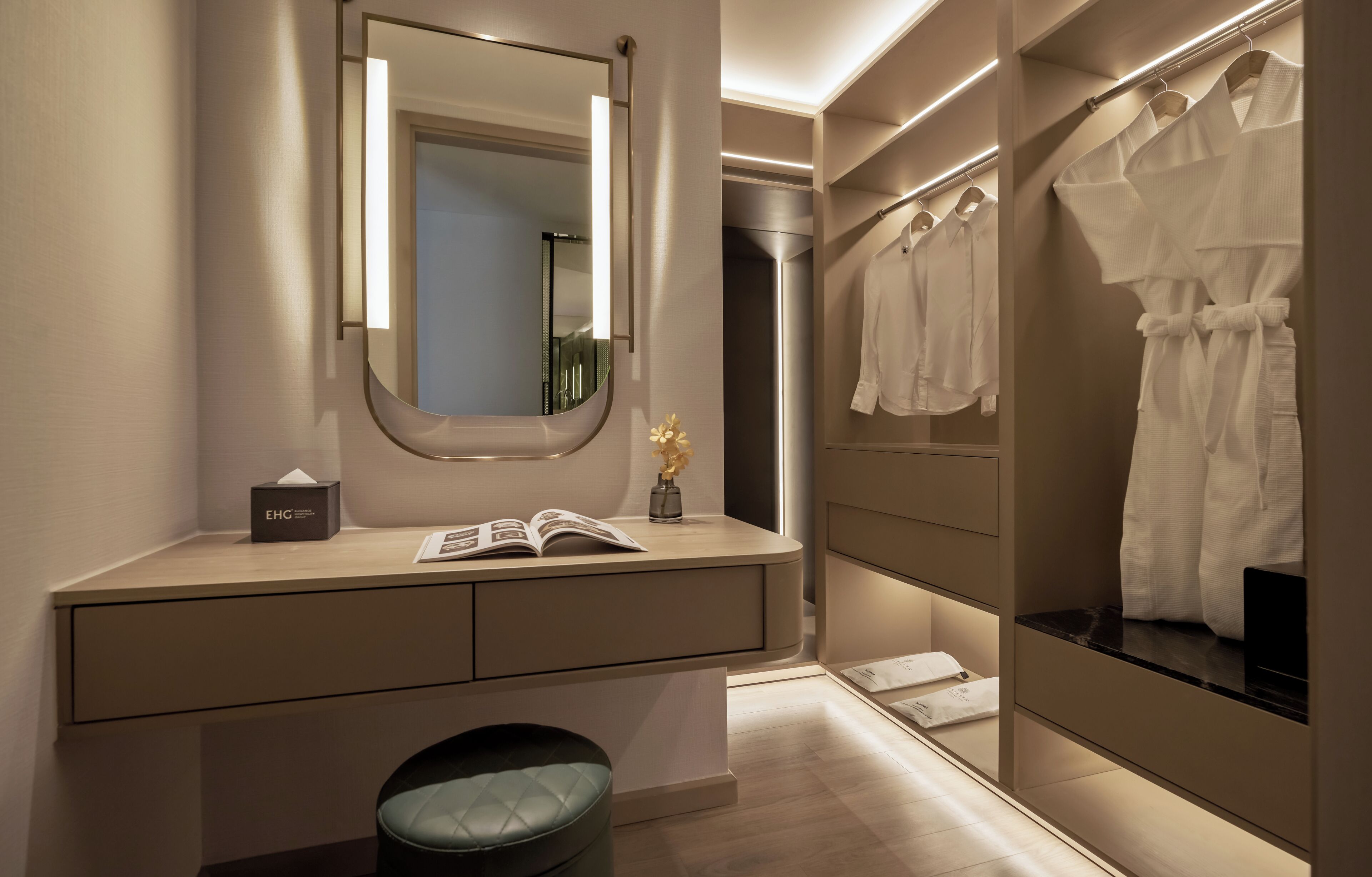 A modern bathroom with a vanity, a mirror, a towel rack, and a small stool.