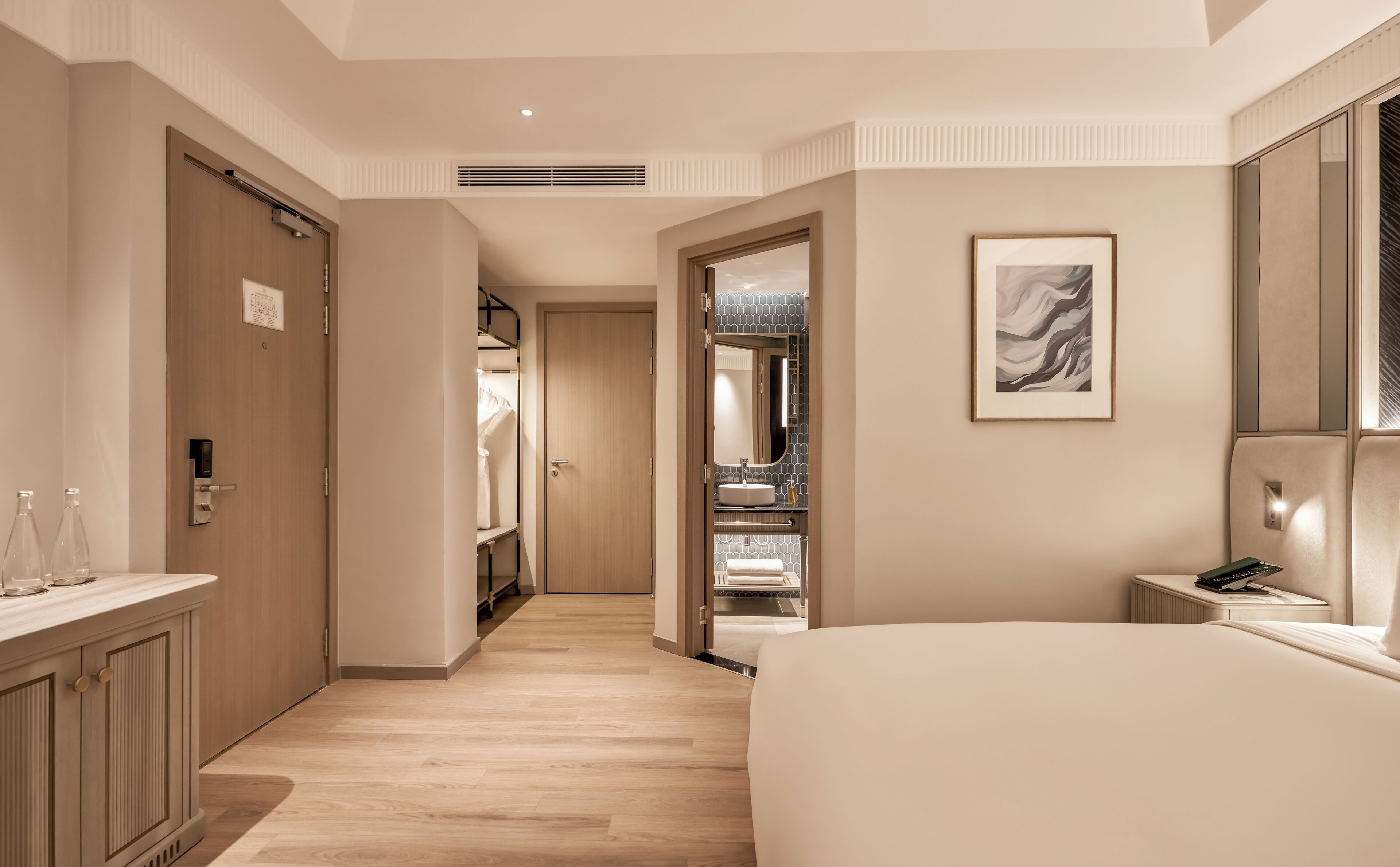 Une chambre d’hôtel moderne dotée d’un grand lit, d’une coiffeuse avec miroir, d’un dressing et d’une œuvre d’art encadrée accrochée au mur.