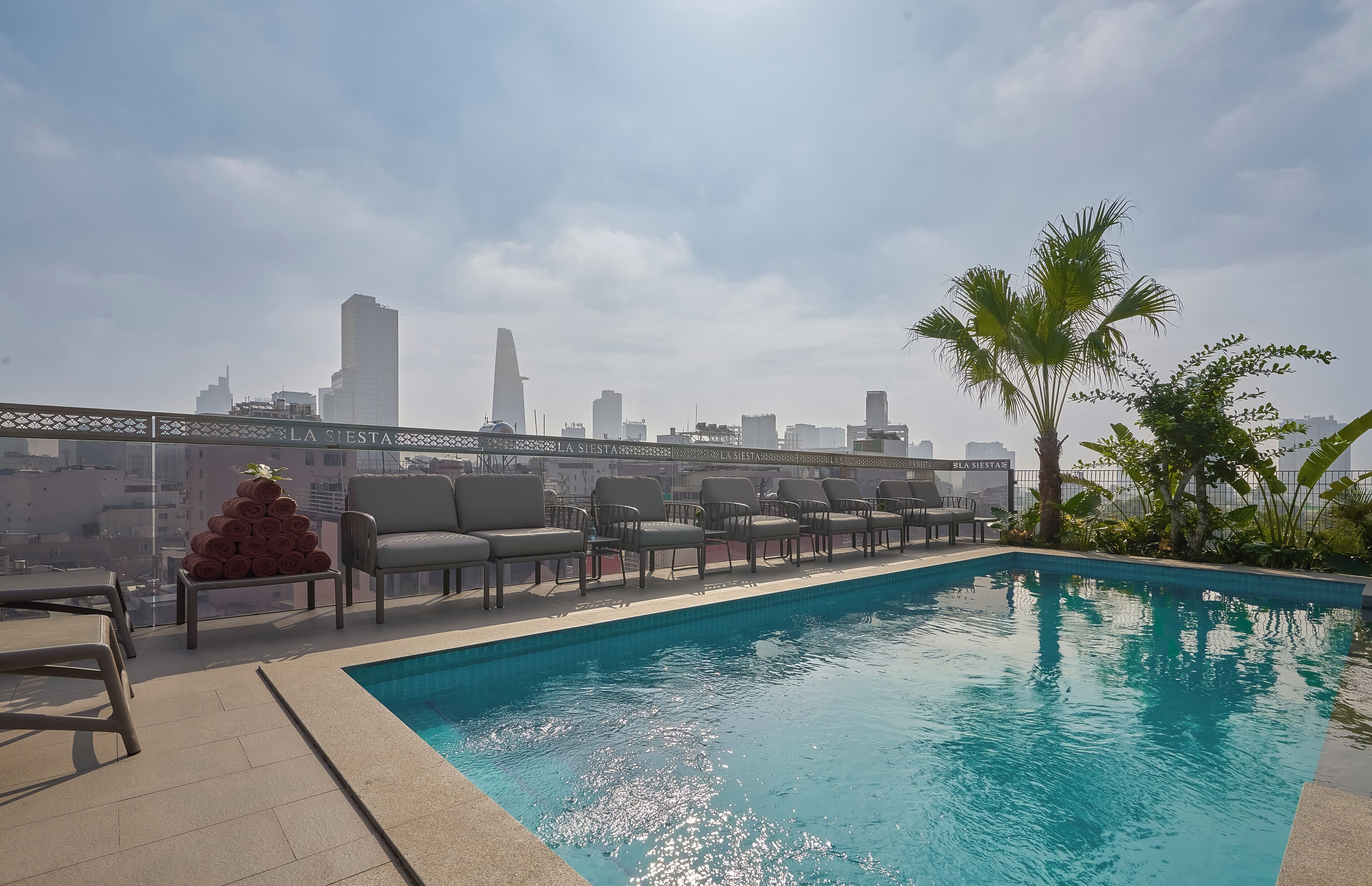 A rooftop pool with lounge chairs and a city skyline view.