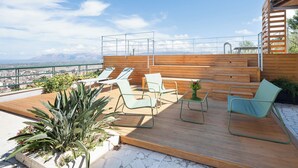 A rooftop terrace with wooden flooring, metal-framed chairs, and a view of a cityscape and mountains. - Detached villa with pool for exclusive use privacy and sea view (Alcamo)