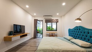 A modern bedroom with a large bed, a TV on a wooden shelf, a desk, and a window with curtains. - LalaHouse Spring Apartment (Ho Chi Minh City)