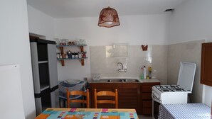 A compact kitchen with a dining table, chairs, a stove, and a sink. - Appartamento in Casa Paiesa, San Fernando Dista in 5 Minuti (Formentera Islas Baleares)