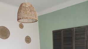 A bedroom with a bed, a woven pendant light, a nightstand, and decorative wall art. - The old Caon grocery store (Telgruc-sur-Mer)