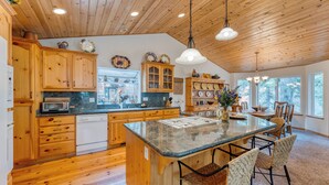 A kitchen with wooden cabinets, a granite countertop, and a central island with bar stools.