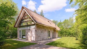 A single-story house with a thatched roof, brick walls, and large windows. - Detached 6-person villa (Ruinen)