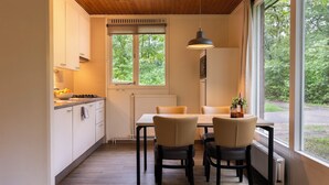 A compact kitchen with a dining area, a large window, and a view of greenery outside.